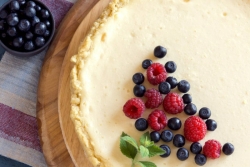 Closeup of a whole cheesecake shot from above and topped with berries